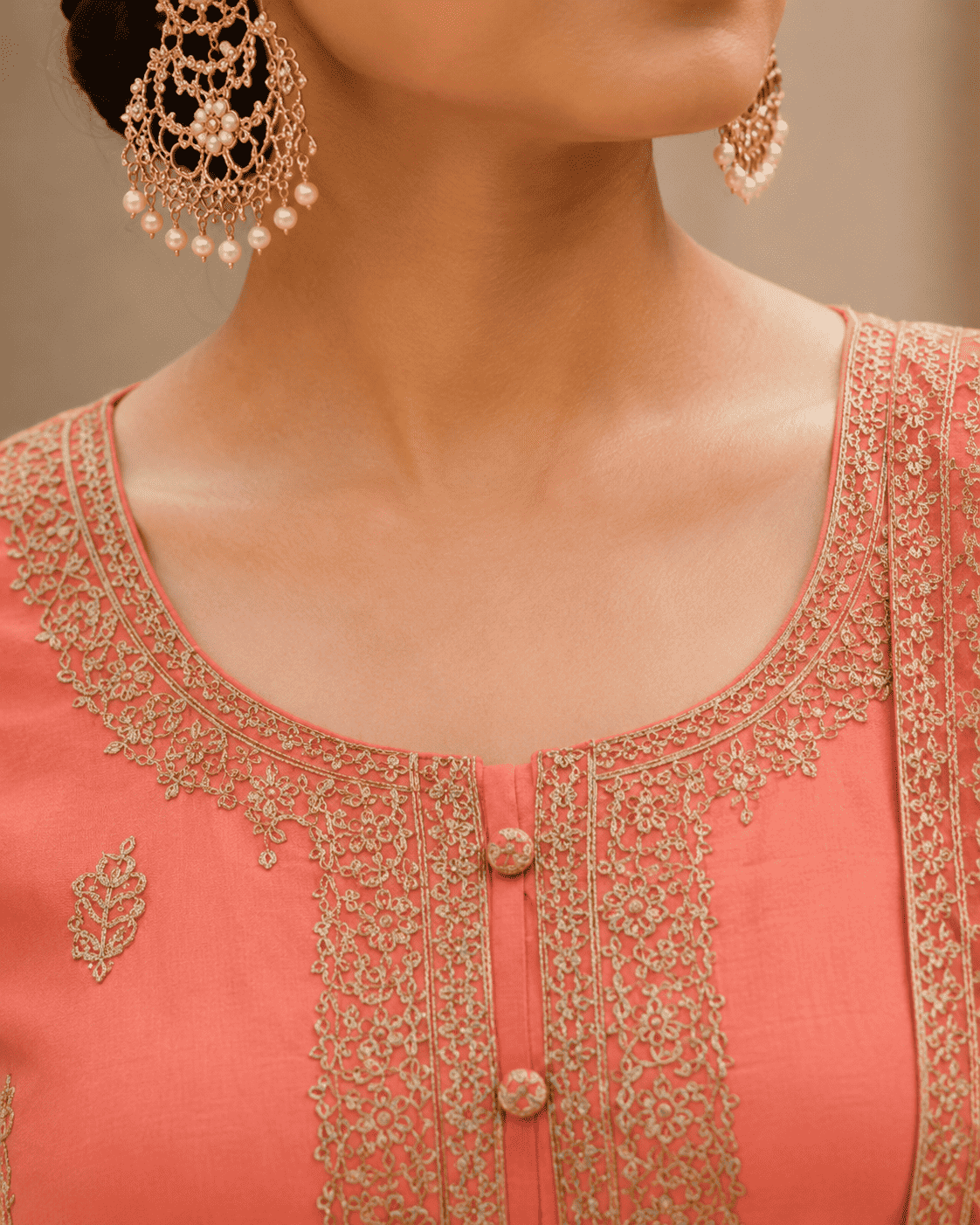Semi-stitched peach cotton suit featuring delicate pastel thread and subtle sequin embroidery. The kurta is adorned with elegant motifs and a finely detailed hem border, paired with matching bottoms and a lightweight embroidered dupatta.