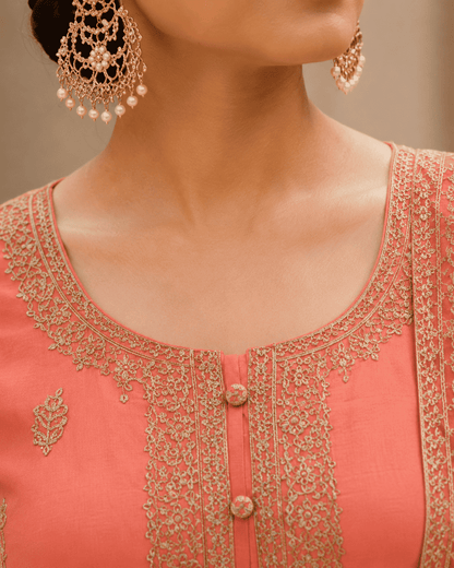 Semi-stitched peach cotton suit featuring delicate pastel thread and subtle sequin embroidery. The kurta is adorned with elegant motifs and a finely detailed hem border, paired with matching bottoms and a lightweight embroidered dupatta.