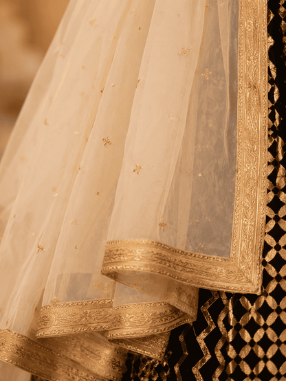 Black cotton silk blouse with ivory geometric printed gota lace lehenga paired with an ivory embroidered organza dupatta