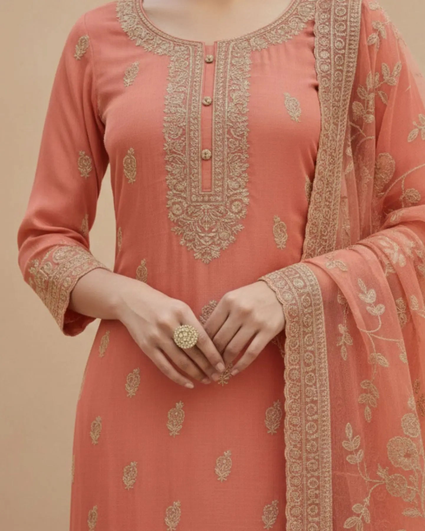 Semi-stitched peach cotton suit featuring delicate pastel thread and subtle sequin embroidery. The kurta is adorned with elegant motifs and a finely detailed hem border, paired with matching bottoms and a lightweight embroidered dupatta.